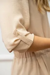 Camisa de seda color beige, de manga larga con presilla y lazo en la cintura para un ajuste elegante.