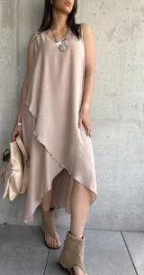 Vestido largo color beige, sin mangas, con escote redondo y corte irregular con volados.