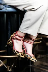 Zapato de tacón con estampado animal print, con doble tira en el tobillo y ribete rojo.