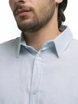 Camisa de manga larga, color blanco, con cuello camisero y botones frontales. El tejido presenta una textura visible de lino.