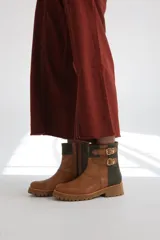 Botas cortas de gamuza color marrón con detalles dorados y hebillas decorativas.