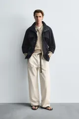 Parka azul marino de tejido técnico, corte relaxed fit, cuello alto ajustable con cordón, manga larga con puños abotonados, cierre frontal con cremallera oculta y solapa con botones a presión, cintura ajustable con cordón interior y bolsillos frontales multifunción de plastrón.
