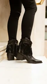 Bota texana de caña corta color marrón, fabricada en cuero con forro de cuero. Presenta cierre lateral y flecos en el tobillo.