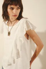 Remera blanca de algodón con mangas cortas con volados de encaje y detalle de volado vertical en el frente.