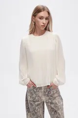 Blusa color crema de poliéster con cuello a la base y mangas largas abullonadas.