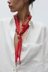Pañuelo bandana de seda color rojo con estampado floral en dorado y cierre ajustable con pieza metálica y aplicación de piedra.
