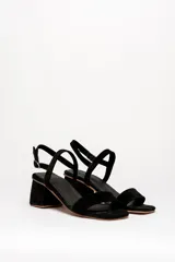 Sandalias negras de cuero gamuzado, con tira fina sobre los dedos y tobillo, y taco cuadrado bajo.