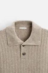 Sweater color beige de punto canalé con cuello polo, solapas amplias y cierre frontal con dos botones.
