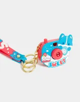Llavero con forma de cámara de fotos azul y roja con strap de silicona con la palabra "Sweet" en letras blancas. Proyecta imágenes (luz y sonido).