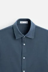 Camisa de vestir azul petróleo, corte regular, confeccionada en mezcla de algodón. Cuenta con cuello solapa, mangas largas con puños abotonados y cierre frontal con botones.