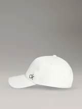 Gorra de béisbol blanca con visera curva y cierre ajustable trasero. Presenta el monograma "ck" bordado en hilo negro en el lateral.