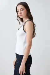 Musculosa de punto canalé color beige con cuello en V y ribete blanco en contraste.