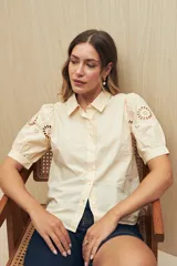 Camisa blanca de mangas cortas abullonadas con calados florales.