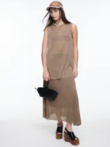 Musculosa sin mangas color gris, tejida en hilado con brillo sutil. De calce relajado y largo por debajo de la cadera, presenta aberturas laterales.