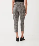 Pantalón capri con estampado tipo tweed en tonos blanco, negro y gris. Tiene corte recto, cintura alta con lazo y bolsillos laterales.