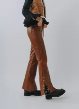 Pantalón de cuero color marrón con corte acampanado y aberturas laterales con botones.