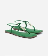 Sandalia plana color verde con tiras finas, cierre en el tobillo, punta cuadrada y detalle de esferas doradas.