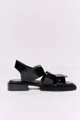 Sandalias de cuero color marrón con tiras anchas cruzadas y hebilla cuadrada.