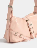 Bandolera hobo color rosa viejo de cuerina, con manija con hebillas regulables laterales, cierre superior y hebilla frontal con broche con imán.