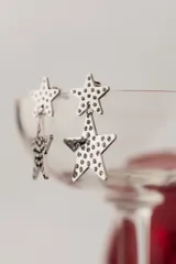 Aros colgantes de acero quirúrgico con baño de oro, con diseño de dos estrellas decoradas con circonias.