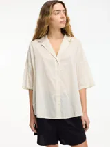 Camisa color crudo con botones en la parte delantera y mangas 3/4. Corte holgado.