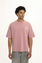 Remera marrón de corte holgado con estampado de una flor en el pecho.