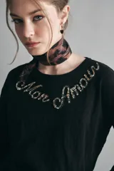 Remera negra de algodón con calce relajado, escote redondo y mangas largas. Presenta un bordado de piedras con la frase 'Mon Amour' en el pecho.