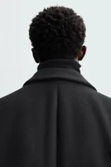 Abrigo negro regular fit confeccionado en paño con lana. Tiene cuello con solapas de muesca, manga larga, bolsillos de solapa en la cadera, bolsillo interior, abertura en el centro de la espalda y cierre frontal con botonadura.