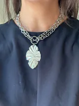 Collar plateado de doble cadena con dije colgante con forma de hoja.