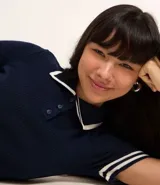 Blusa de punto azul marino con cuello polo blanco, abotonada al frente, de manga corta con rayas blancas en los puños y en el ruedo. Corte ajustado.