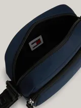 Bandolera azul marino de poliéster reciclado con correa ajustable con logo Tommy Jeans en blanco y negro. Presenta cierre de cremallera, bolsillo exterior con cremallera y parche con logo Tommy Jeans en el frente.