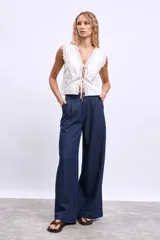 Chaleco blanco con escote en V, detalle de encaje y lazos en el frente.