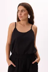 Musculosa negra de breteles finos y corte holgado.