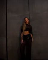 Pantalón largo negro, de tejido transparente con franjas horizontales opacas, corte recto y tiro alto. Se lleva sobre otra prenda.