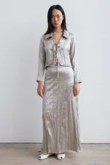 Falda larga acampanada color beige claro, con textura plisada y cierre invisible en la espalda.