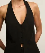 Chaleco negro con frente única, corte peplum, estructura sastre y cierre frontal con botones.