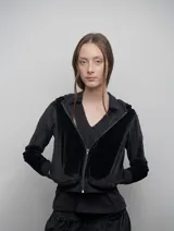 Campera de terciopelo negro brilloso con capucha, cierre frontal, bolsillos laterales, puños y cintura ajustados. Silueta relajada.