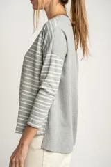 Sweater oversize gris con rayas horizontales blancas, de tejido suave y mangas largas.