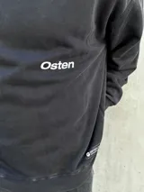 Buzo negro de corte holgado con estampa en la espalda que incluye una estrella blanca, la palabra "Osen" y las palabras "Empower", "Elevate", "Boldness" y "Strength".