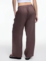 Pantalón negro de lino con elástico en la cintura y calce relajado. Incluye bolsillos laterales y un bolsillo invertido. Detalles de bordado tipo pespunte en color gris recorren la pierna y el bajo.