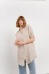 Camisa color beige de lino, con corte recto y calce suelto, cuello camisero, botones en el frente y mangas cortas con presilla y botón.
