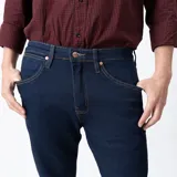 Jean de corte slim fit color azul oscuro con costuras en color ocre.