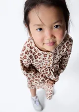 Vestido infantil de manga larga con estampado de leopardo en tonos beige y marrón.