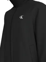 Campera negra con capucha de nailon reciclado, cierre frontal con cremallera, bolsillos laterales con botón a presión, puños y bajo elásticos, forro ligeramente acolchado y logo de Calvin Klein en el pecho y la manga.