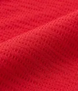 Vestido midi rojo de malla texturizada, con escote en pico, mangas cortas, aro central en el escote y recorte cutout lateral en la cintura.