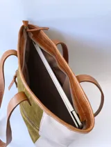 Bolso tipo tote de cuero color verde oliva con laterales de cuero texturizado color beige y manijas de cuero color marrón.