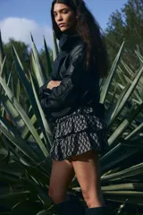 Minifalda negra con estampado floral blanco, cintura alta con elástico en la parte posterior y volados escalonados.