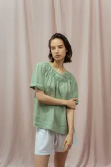 Blusa verde de lino con escote redondo fruncido y mangas cortas.