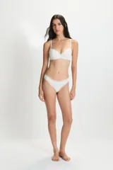 Conjunto de lencería blanco, compuesto por un corpiño soft con aro y detalles de encaje en el borde superior, y una bombacha tipo colaless con elástico de encaje en la cintura.