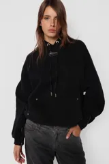 Buzo hoodie negro de frisa, corte oversize, con puños y cintura de rib al tono, capucha forrada y bolsillo canguro. Detalle de remaches en la boca del bolsillo, cierre metálico niquelado en el puño de las mangas, cordones con ojalillos y punteras personalizadas de marca. Cordones atracados en delantero con bordado de marca.